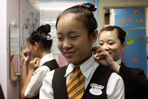 店长陈洁帮助两名女生在更衣室内换上制服,并梳理规定的发型。